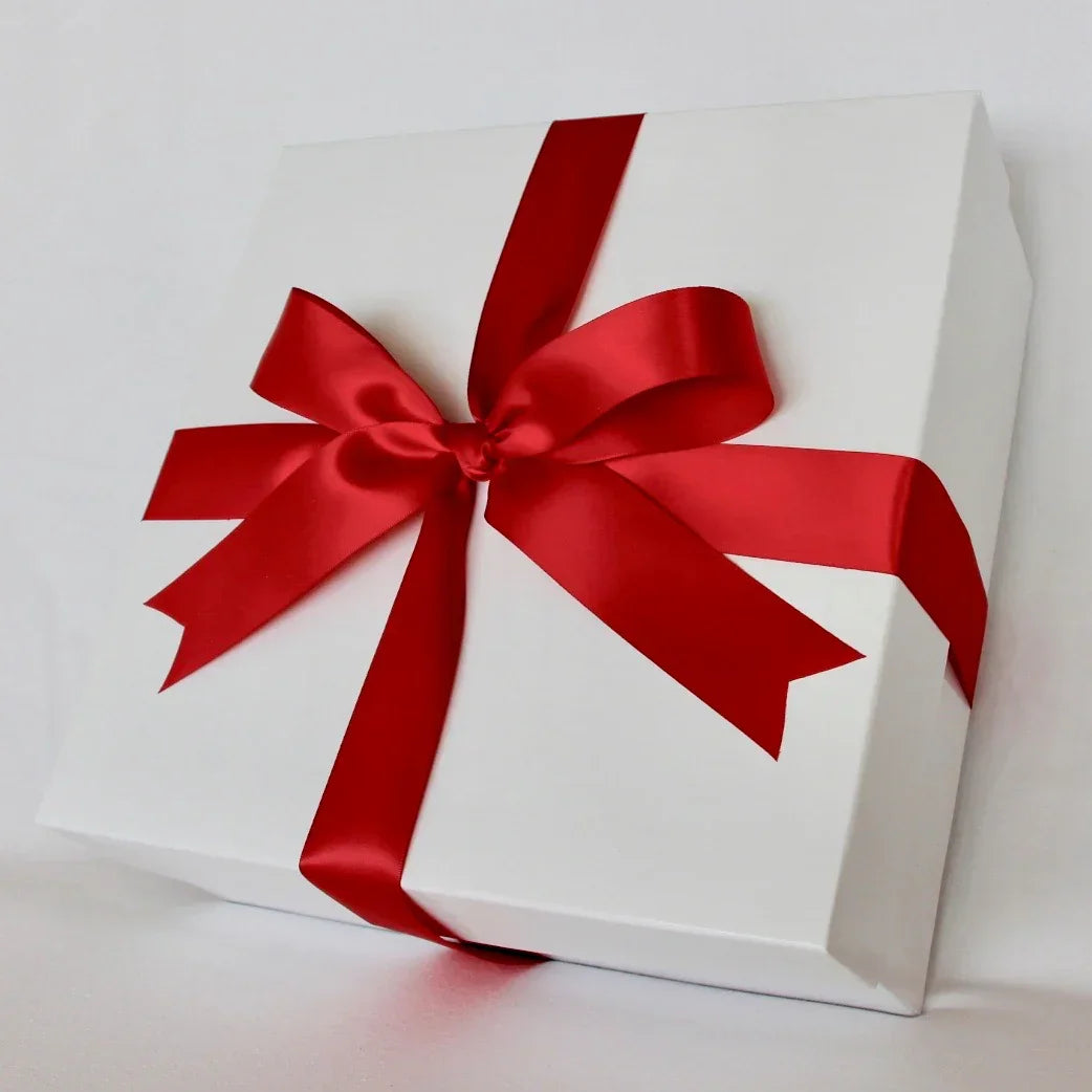 White gift box wrapped with a shiny red satin ribbon and bow on white background